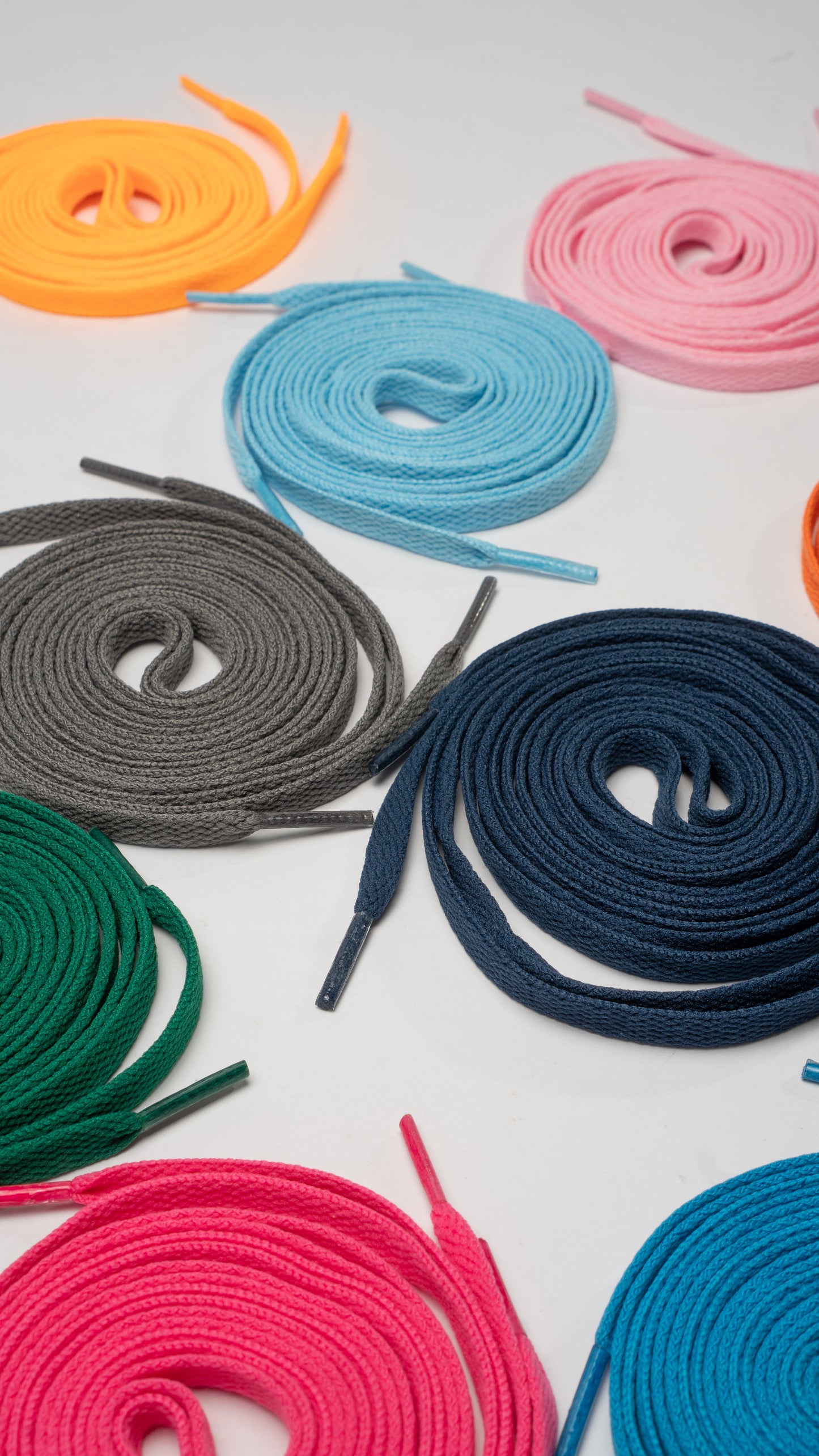 Colorful shoelaces arranged on a light gray background